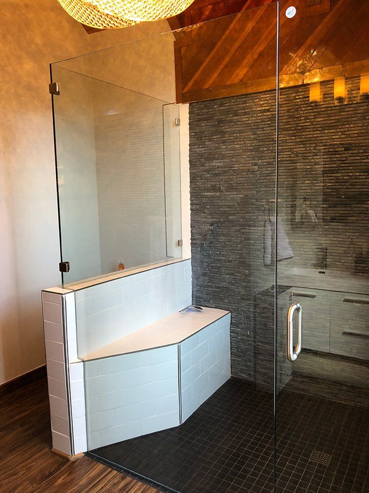 A bathroom with a walk in shower with a glass door and a bench