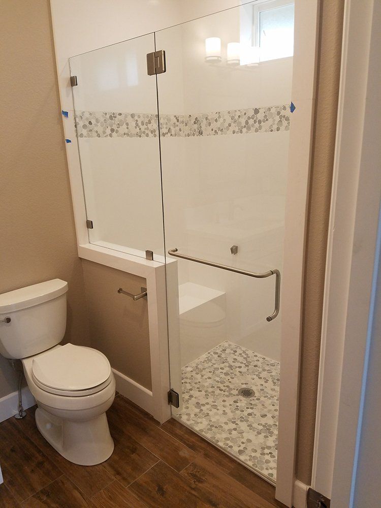 A bathroom with a toilet, shower and glass door