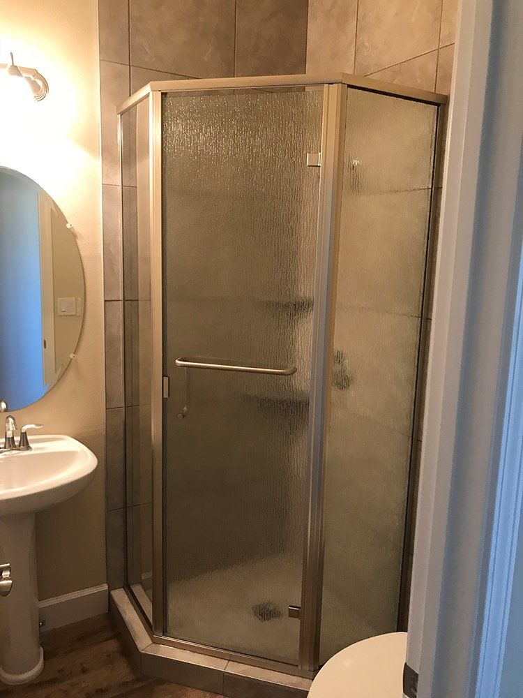 A bathroom with a shower, sink, toilet and mirror