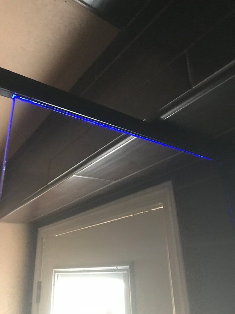A blue light is hanging from the ceiling of a room next to a window