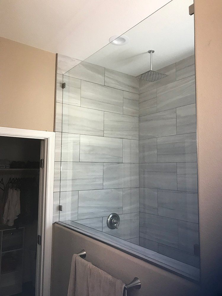 A bathroom with a glass shower door and a towel rack
