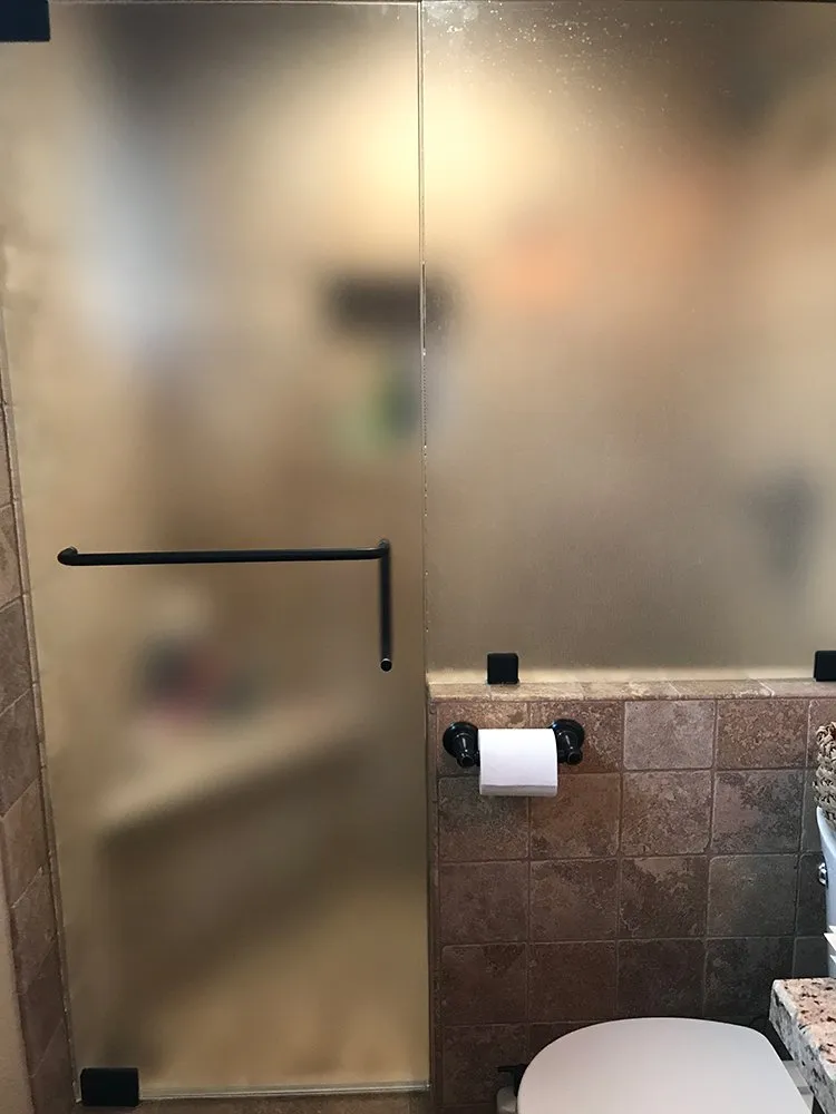 A bathroom with a toilet and a glass shower door