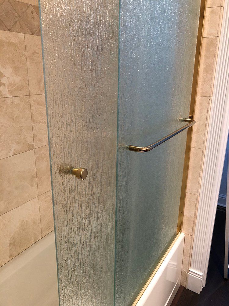 A bathroom with a glass shower door and a bathtub