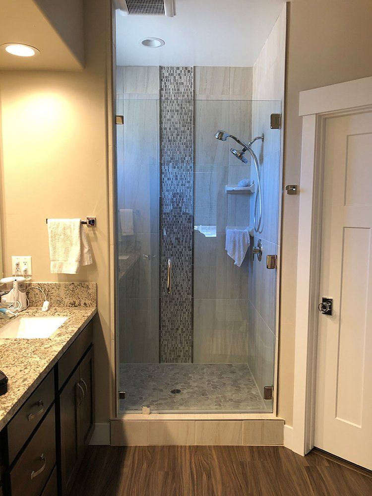 A bathroom with a walk in shower and a sink