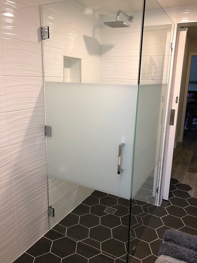 A bathroom with a glass shower door and black tiles