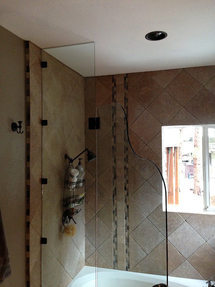 A bathroom with a glass shower door and a tub