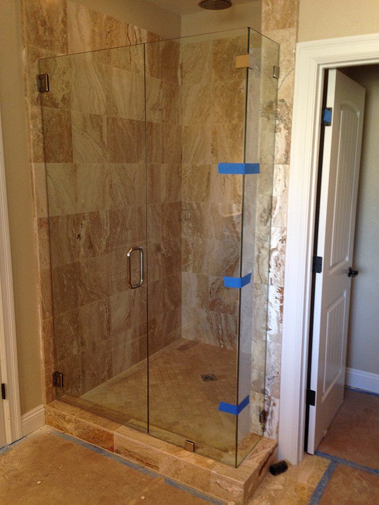 A bathroom with a walk in shower with a glass door