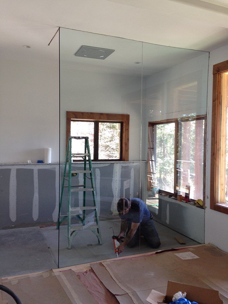 A man is working on a glass wall in a room