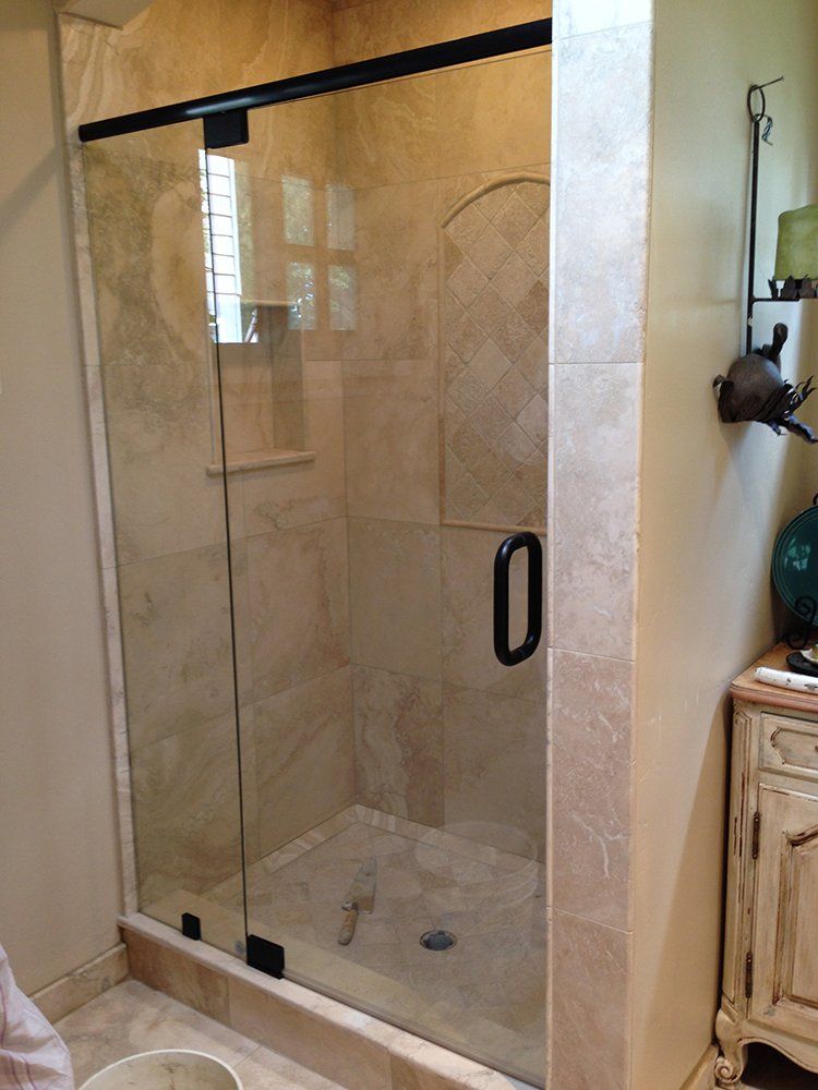 A bathroom with a glass shower door and a nightstand