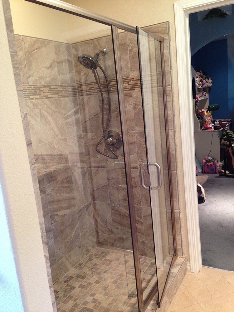 A bathroom with a walk in shower with a glass door