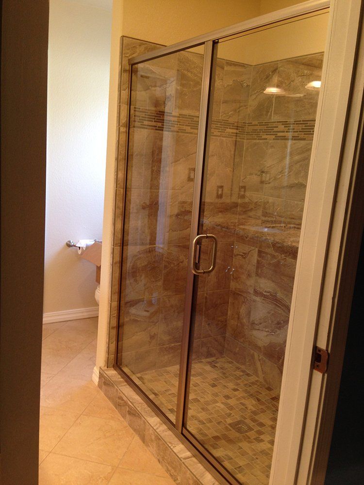 A bathroom with a walk in shower with a glass door