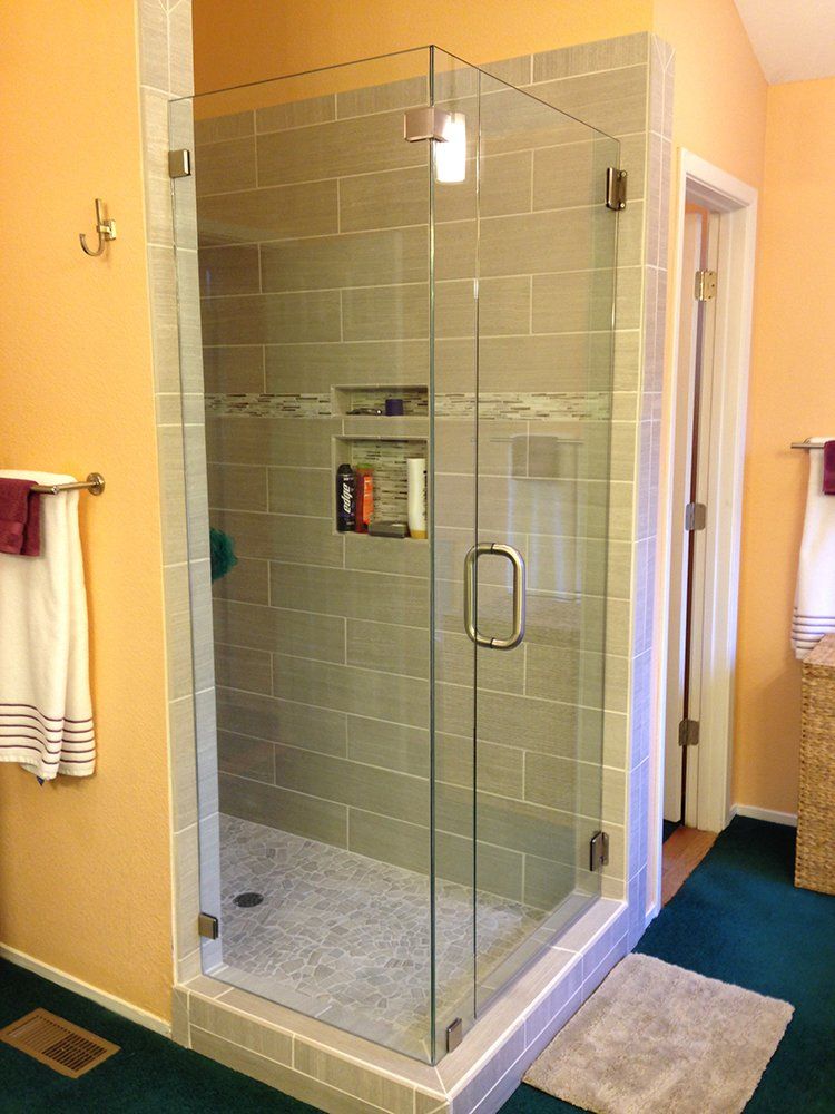 A bathroom with a walk in shower with a glass door