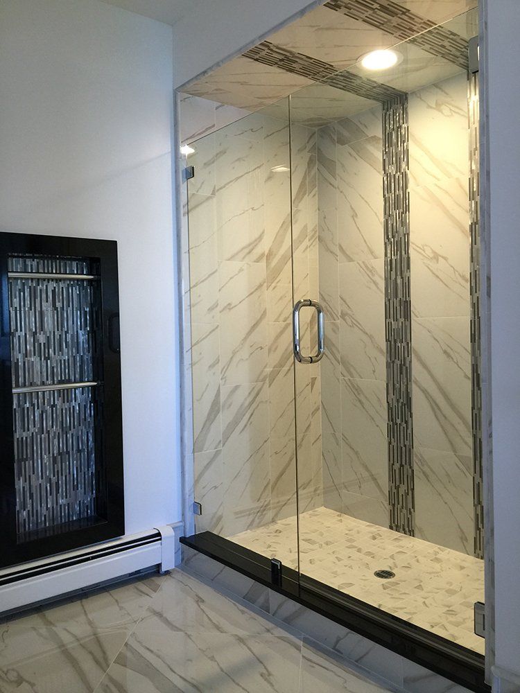 A bathroom with a walk in shower with a glass door