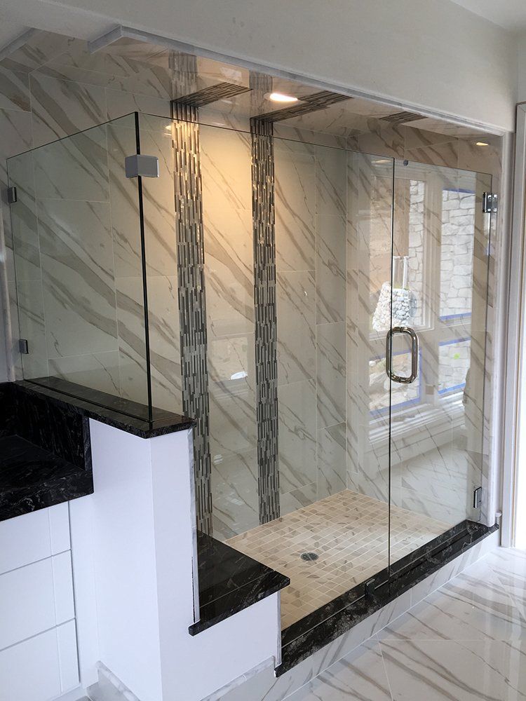 A bathroom with a glass shower door and marble walls