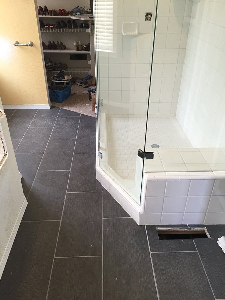 A bathroom with a walk in shower and a closet filled with shoes