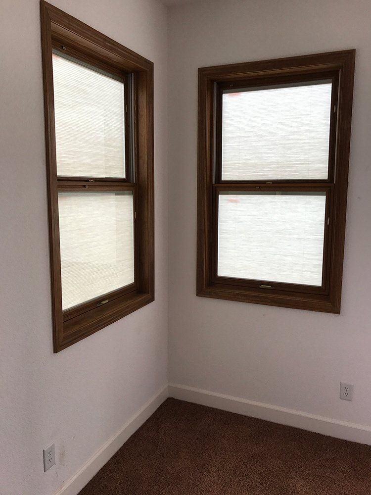 A room with two windows and a brown carpet
