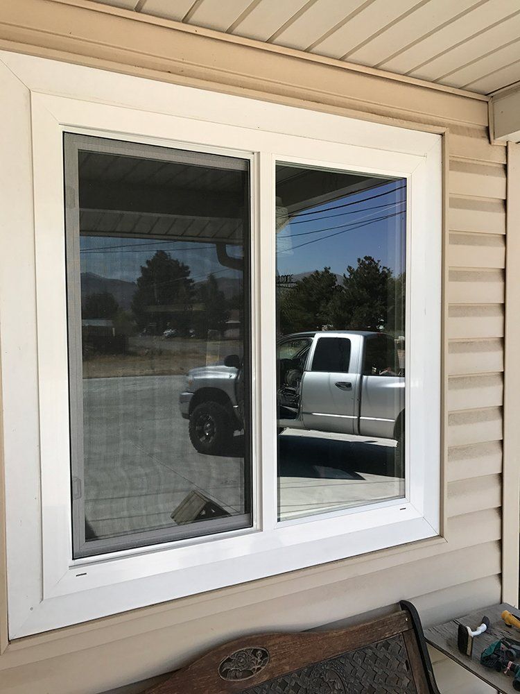 A truck is parked in front of a window on the side of a house