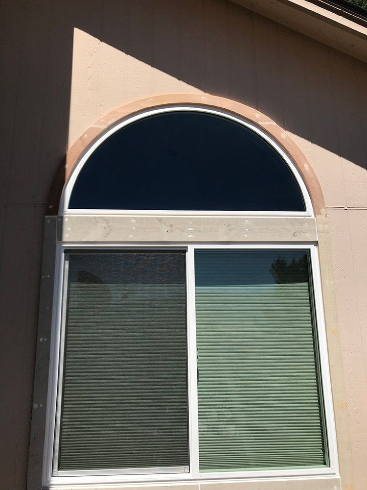 A large arched window with blinds on it is on the side of a building
