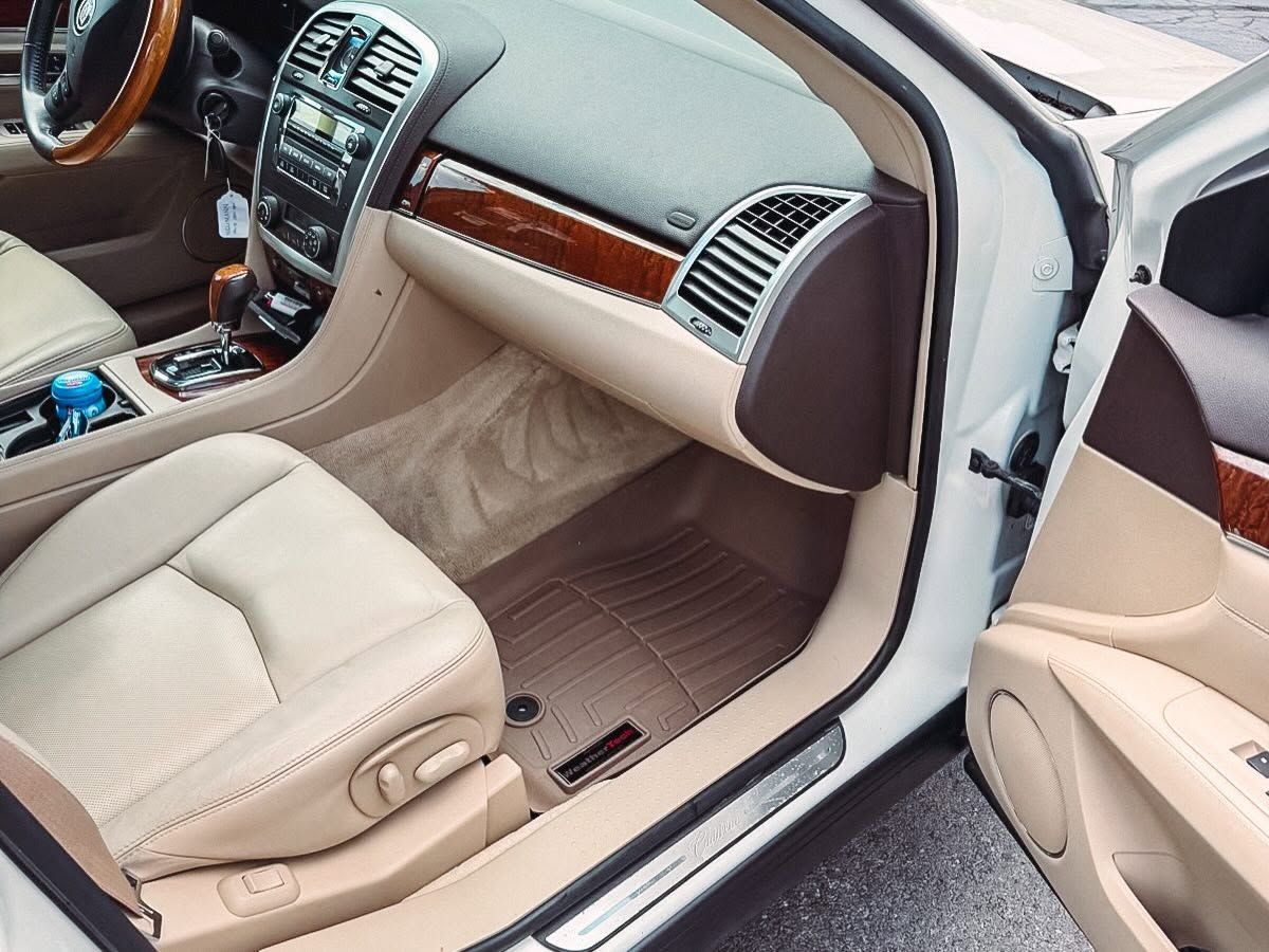 Light beige car interior with open door, dashboard, center console, and front passenger seat visible