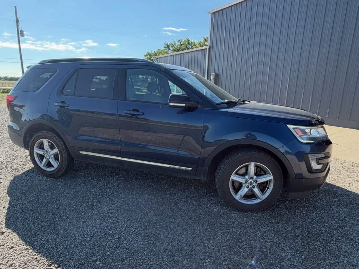 Dark blue SUV parked on gravel beside a metal building under a clear sky.