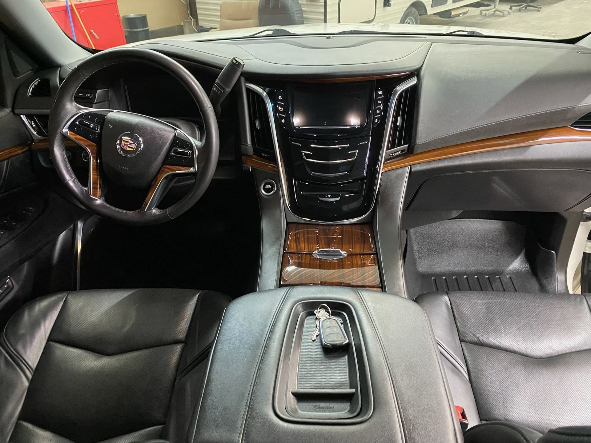Luxury car interior with black leather seats, wood trim, and a Cadillac steering wheel and dashboard
