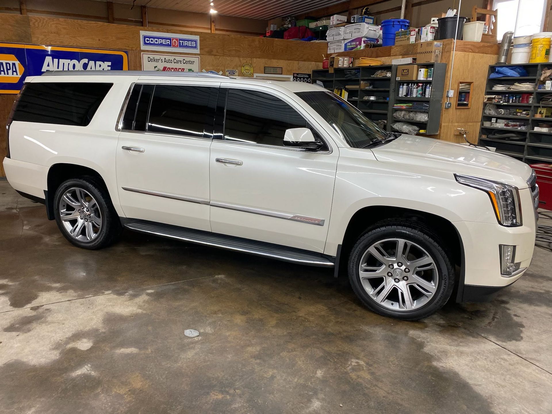 White SUV parked inside an auto repair shop with tools and shelves in the background