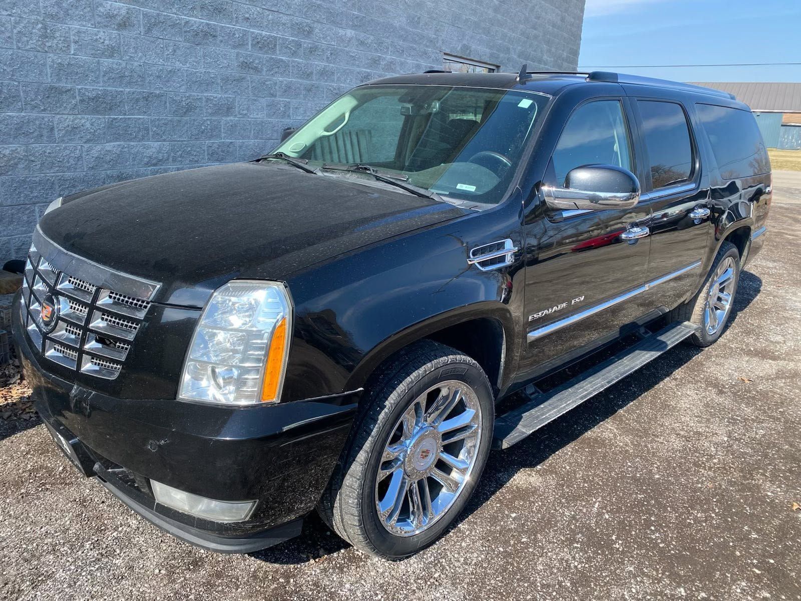 Black Cadillac Escalade SUV parked on a sunny lot, front-left view.