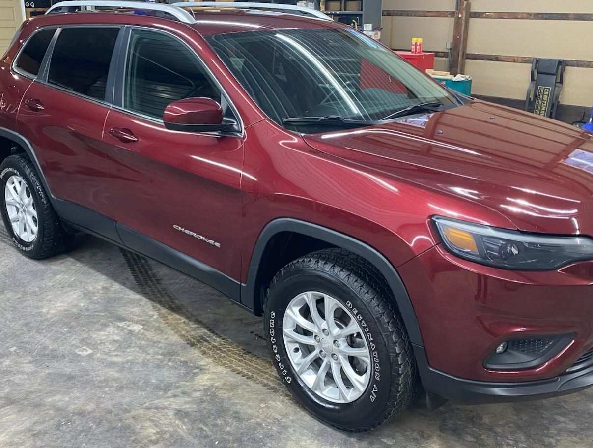 Red SUV parked indoors in a garage, shown from the front-left side.