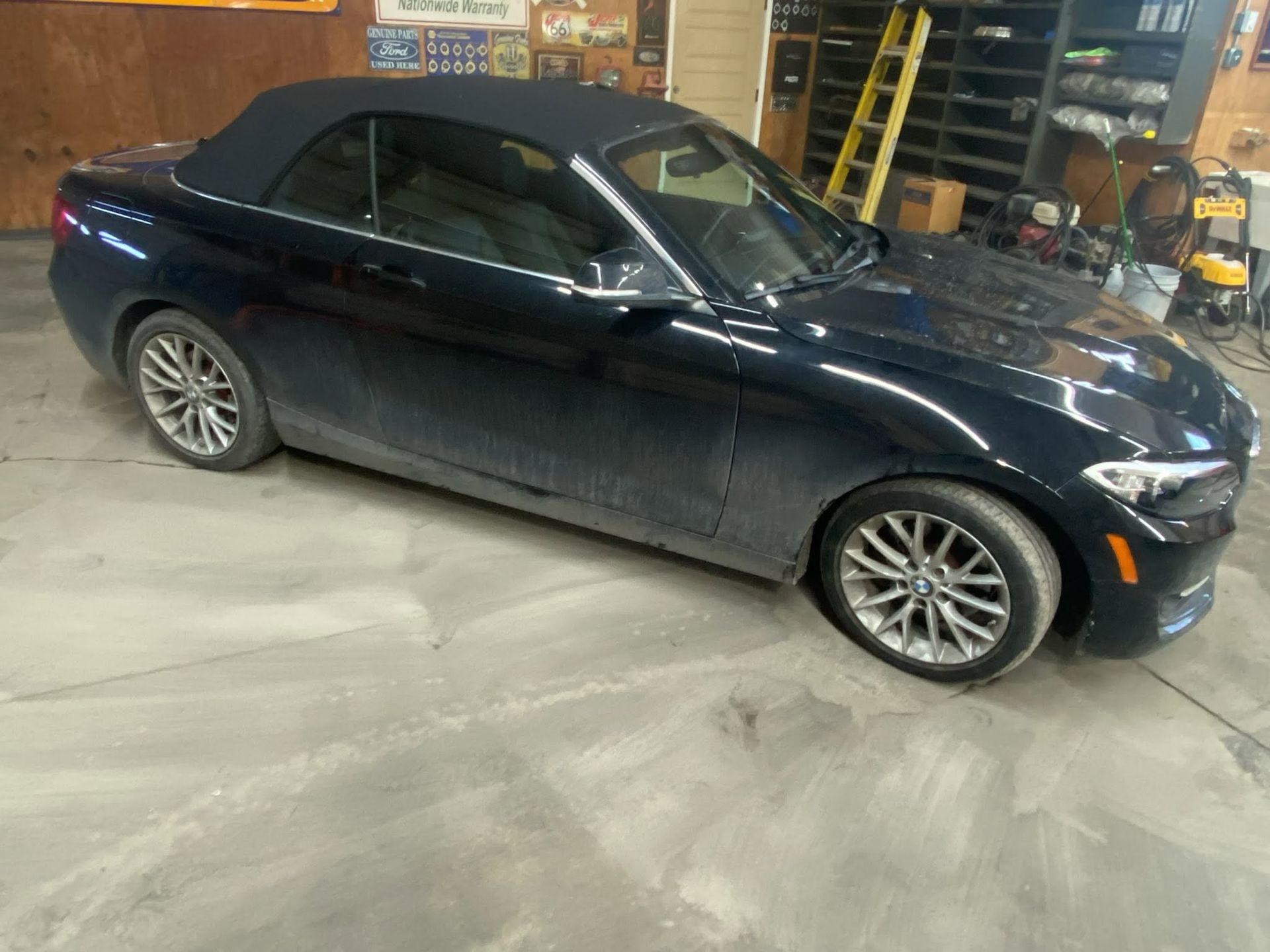 Dark blue sedan parked inside a garage or workshop, viewed from the side.