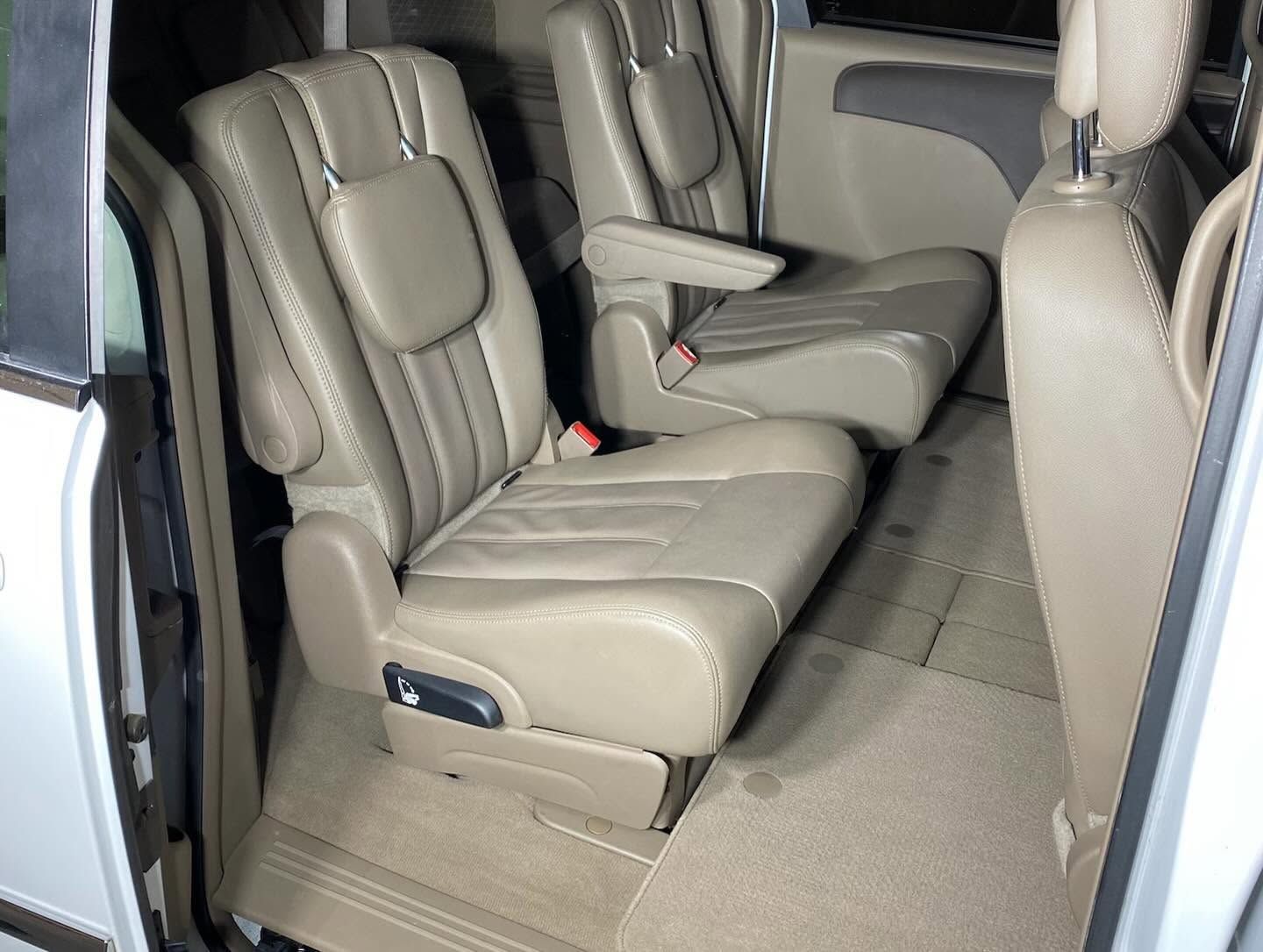 Tan leather second-row car seats with armrests and a bench-style center seat inside an SUV