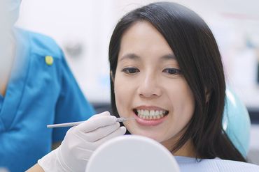 Patient looking at her teeth through the mirror