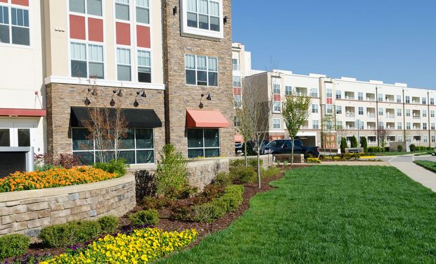 A large apartment building with a lush green lawn in front of it