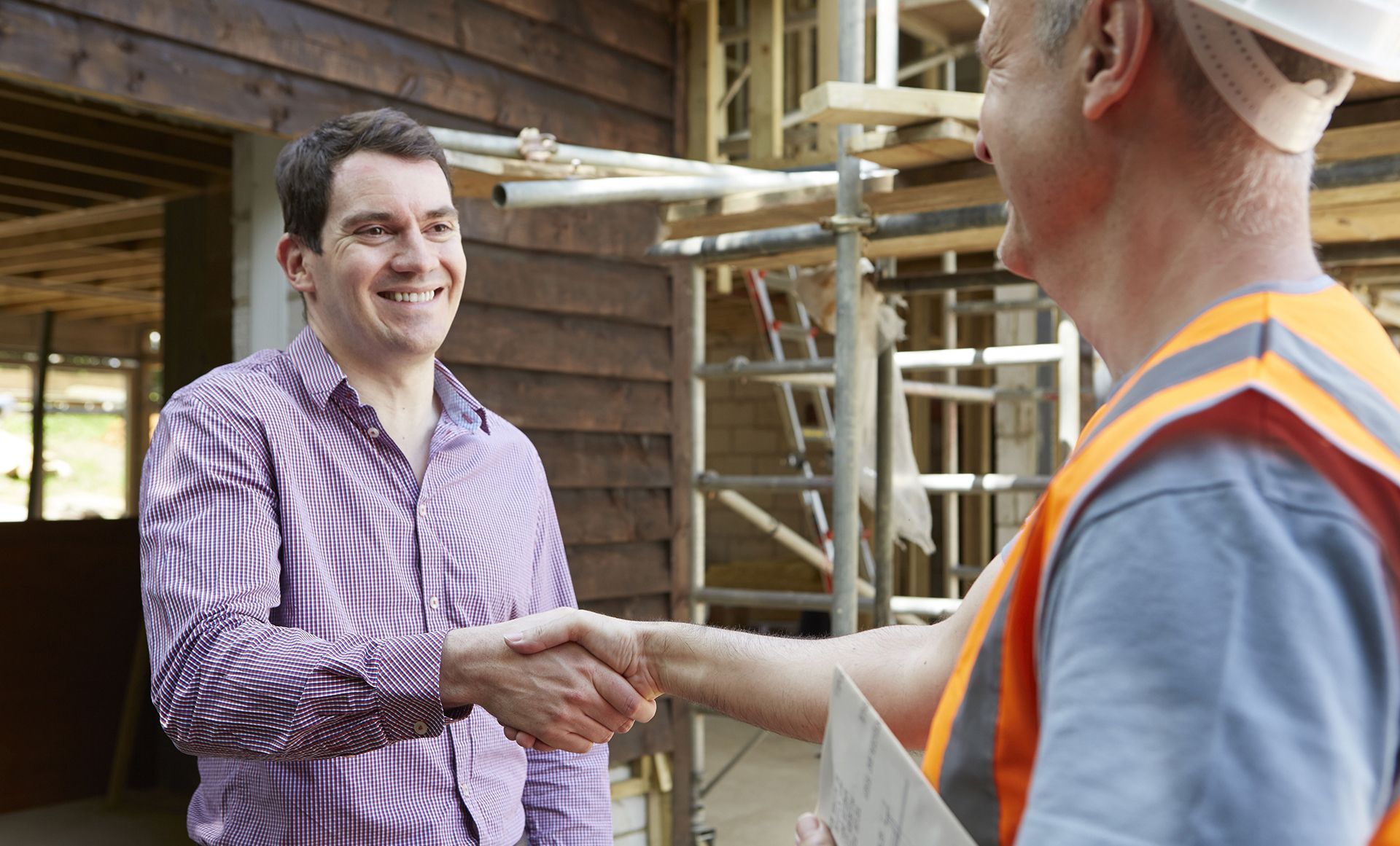 A man is shaking hands with a construction worker at a construction site.