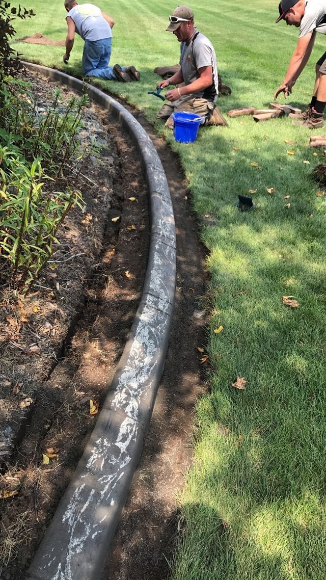 a group of men are working on a concrete curb in a yard .