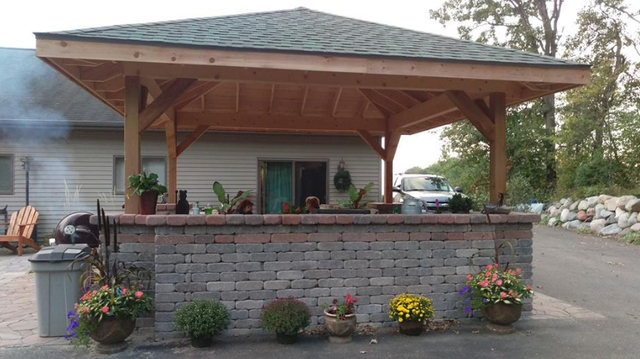 a large wooden gazebo is sitting in front of a house .