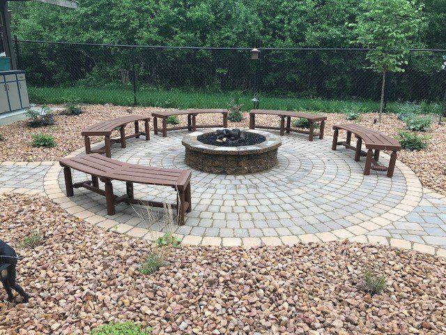 there is a fire pit in the middle of the patio with benches around it .