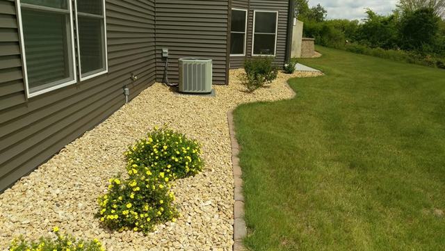 a house with a lawn and gravel in front of it .
