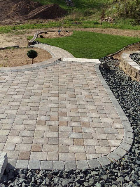a brick walkway leading to a lush green field