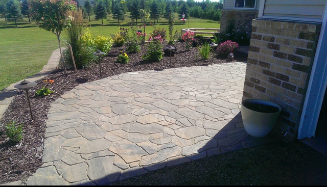 a patio with a brick wall and a potted plant in front of a house .