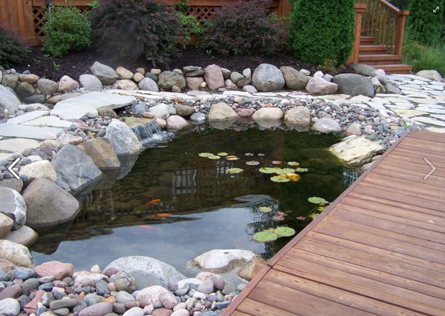 a pond surrounded by rocks and a wooden deck