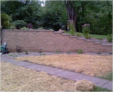 a brick wall is surrounded by hay bales and a sidewalk .