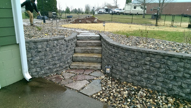 a stone wall with stairs leading up to it next to a house .