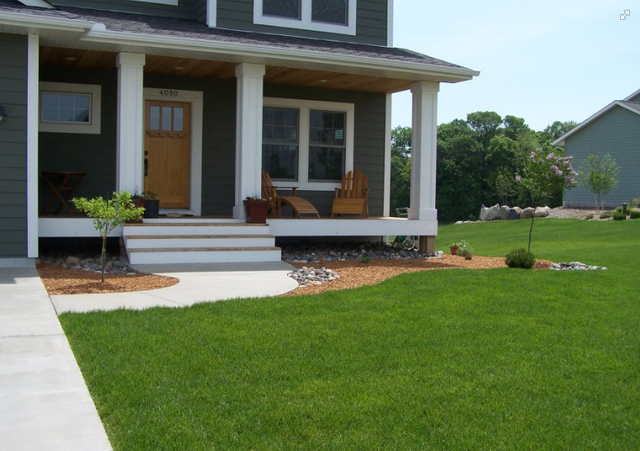 a house with a porch and a lush green lawn