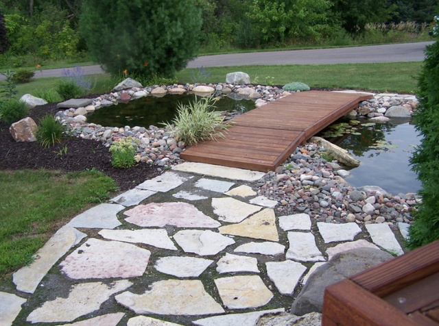 a wooden bridge over a pond in a garden