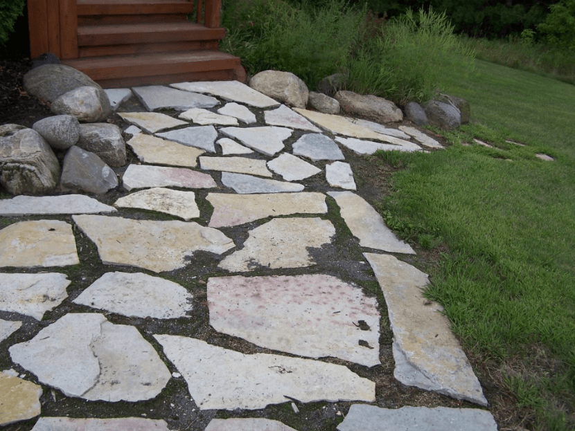 a stone walkway with a wooden staircase in the background