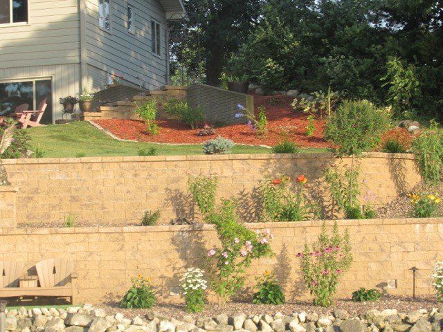 a house sits on top of a hill with a brick wall surrounding it