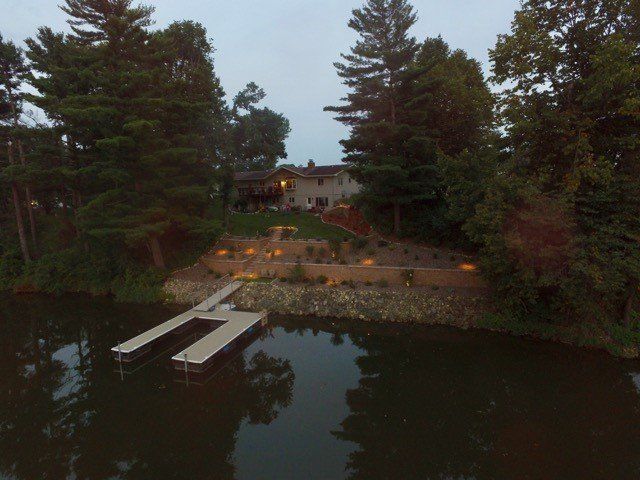 an aerial view of a lake with a dock and a house in the background
