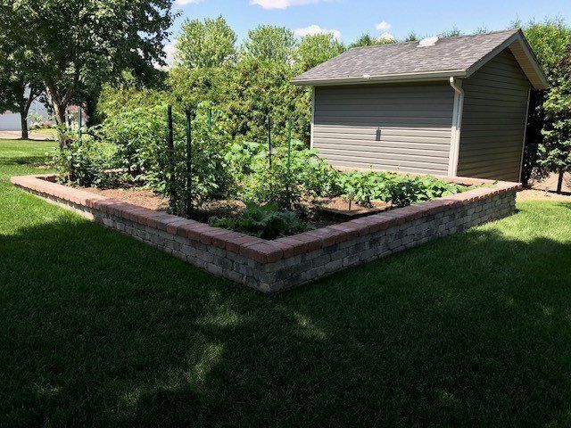 a garden with a brick wall and a shed in the background .