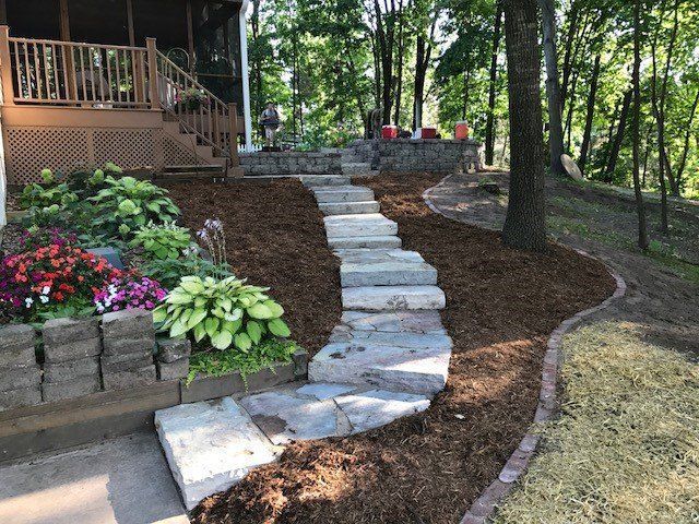 a stone walkway leading to a house in the woods .