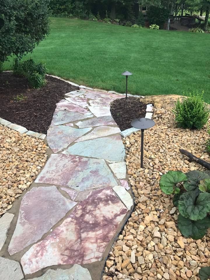 a stone walkway leading to a lush green lawn .